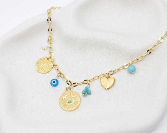 Gold necklace with various charms on a white background
