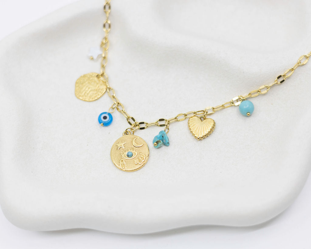 Gold necklace with various charms on a white surface