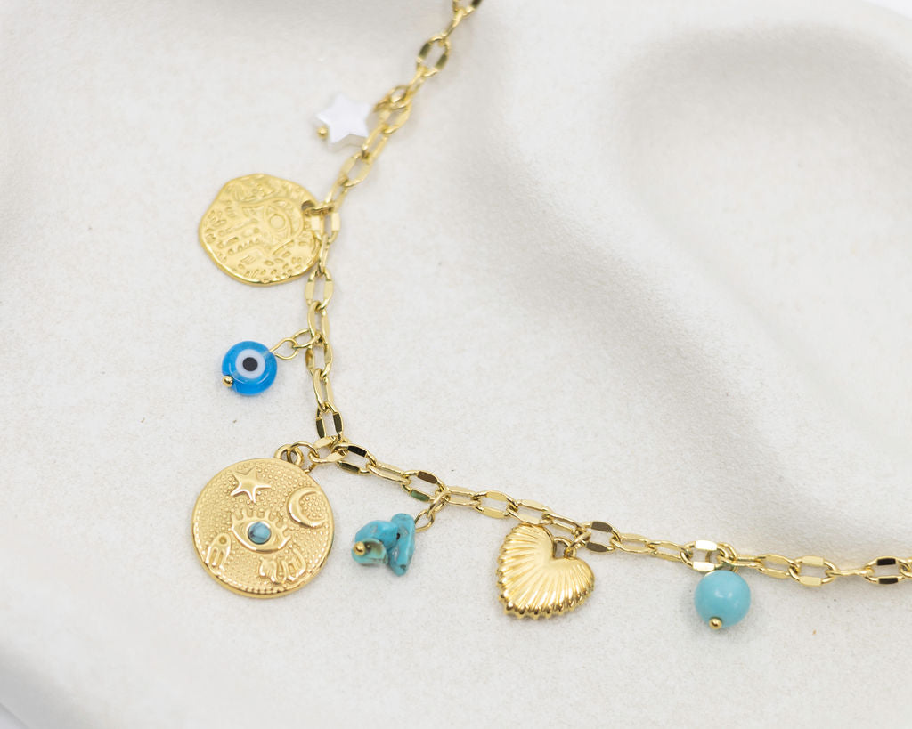 Gold necklace with various charms on a light background