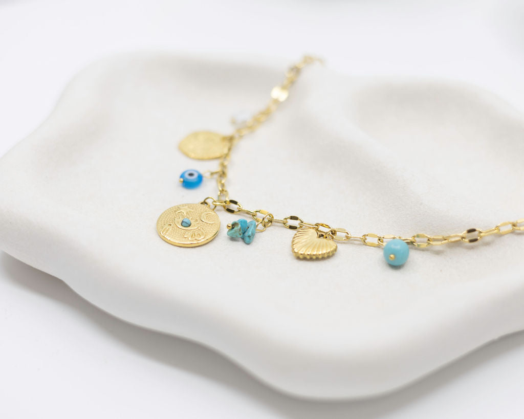 Gold necklace with blue beads on a white surface