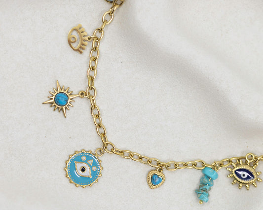 Gold bracelet with various charms including blue stones and eye designs on a white background