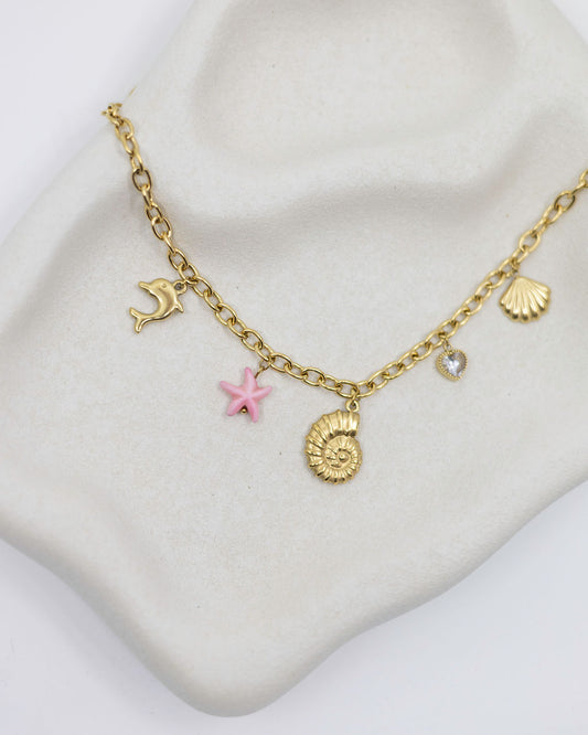 Gold necklace with sea charms on a white surface