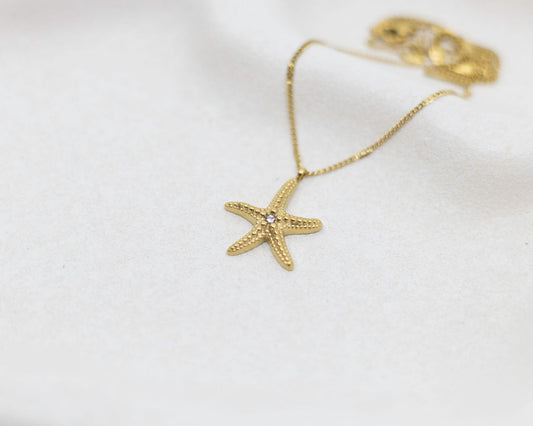 Gold starfish pendant necklace on a white background