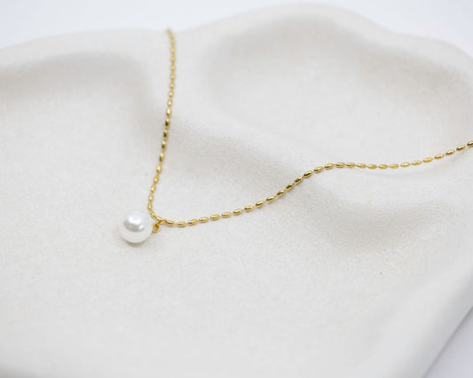 gold chain necklace with round pearl drop on white background