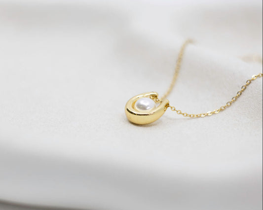Gold necklace with a pearl pendant on a white background