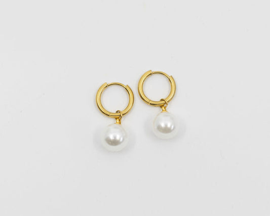Gold hoop earrings with pearl drops on a light gray background
