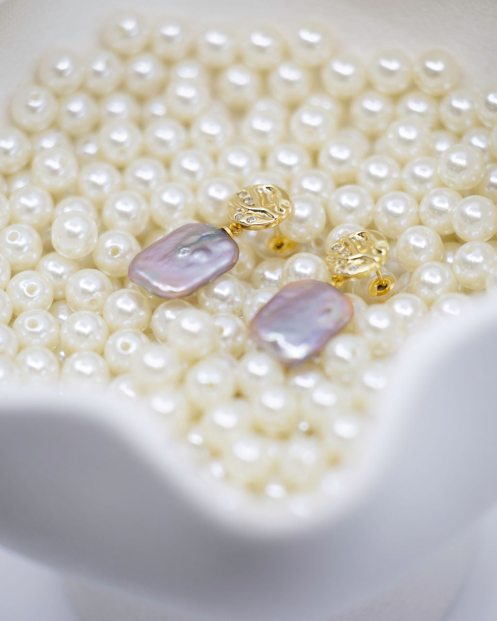 Pearl earrings with gold clasps on a bed of pearls