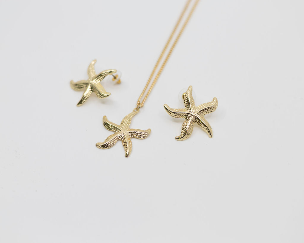 Gold starfish necklace and earrings on a light gray background