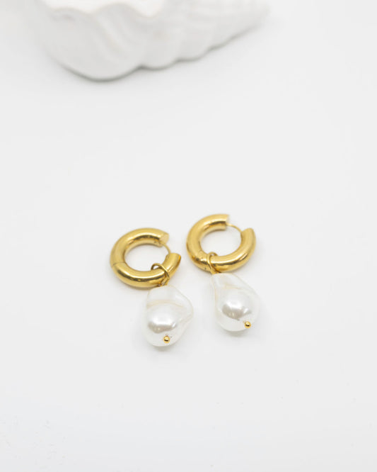 Gold hoop earrings with pearl drops on a white background