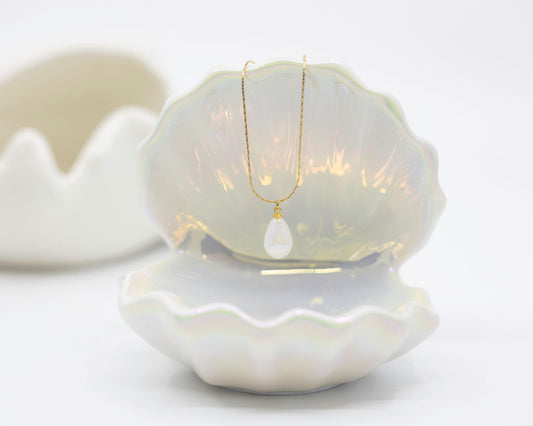 gold necklace with pearl drop on white background