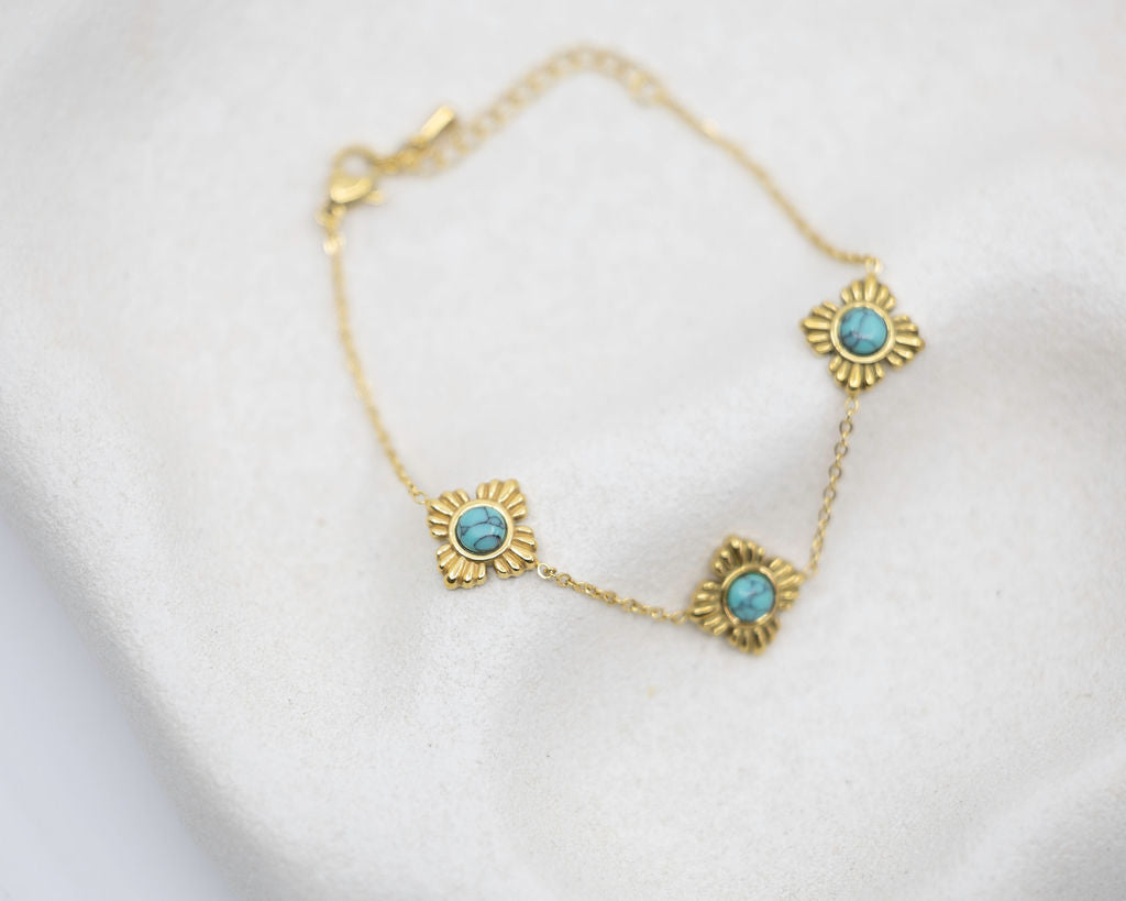 Gold bracelet with turquoise stones on a white background