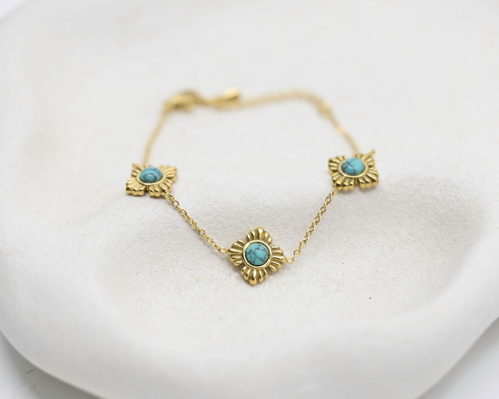 Gold necklace with turquoise stones on a white surface