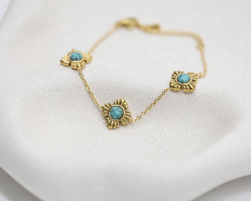 Gold bracelet with turquoise stones on a white background
