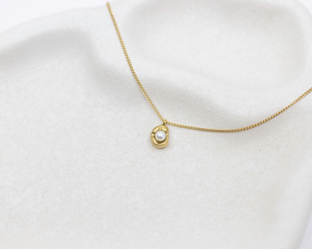 Gold necklace with a pearl pendant on a white background