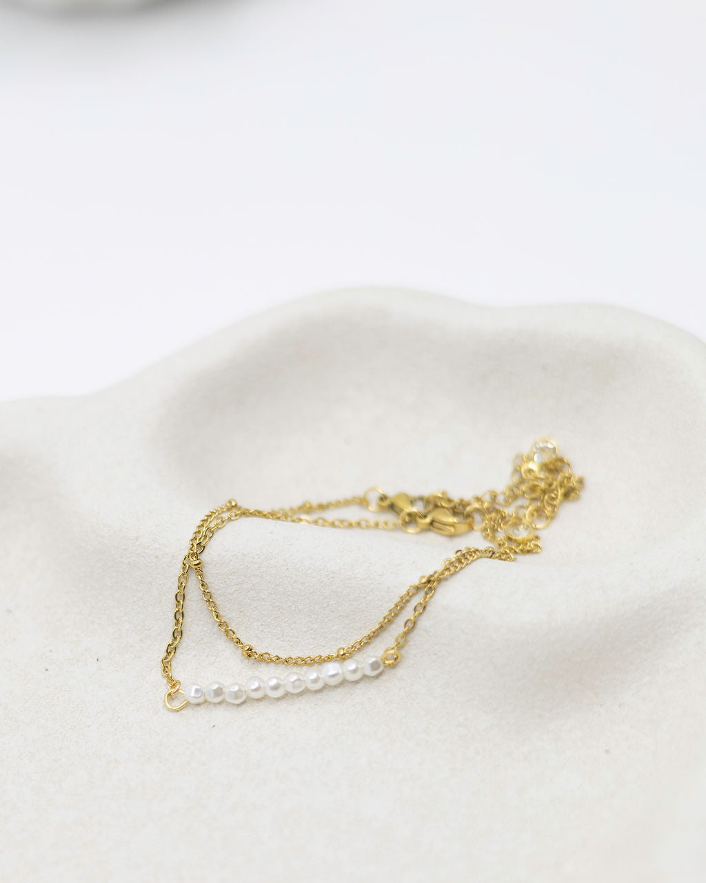 Gold and pearl necklace on a white surface