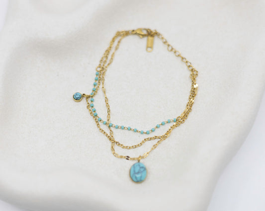 Gold necklace with turquoise beads on a white background
