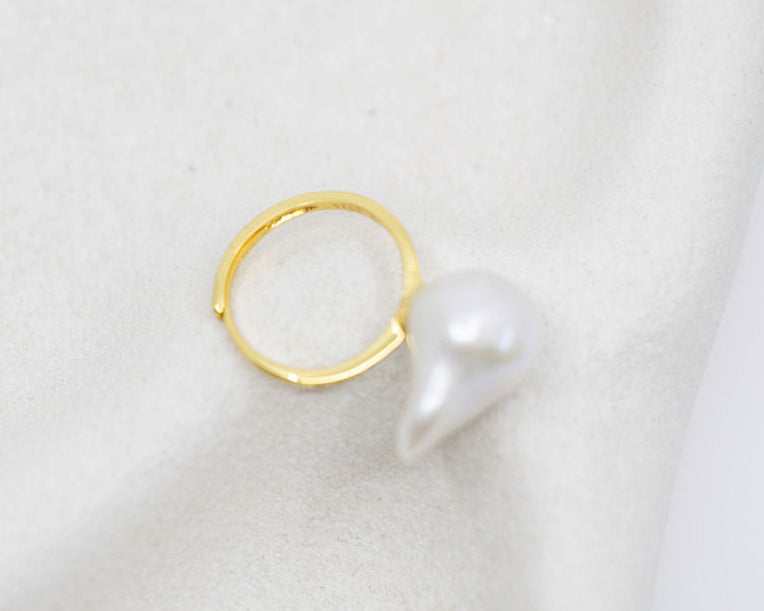Gold ring with a pearl on a light grey background