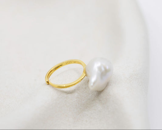 Gold ring with a pearl on a soft white background