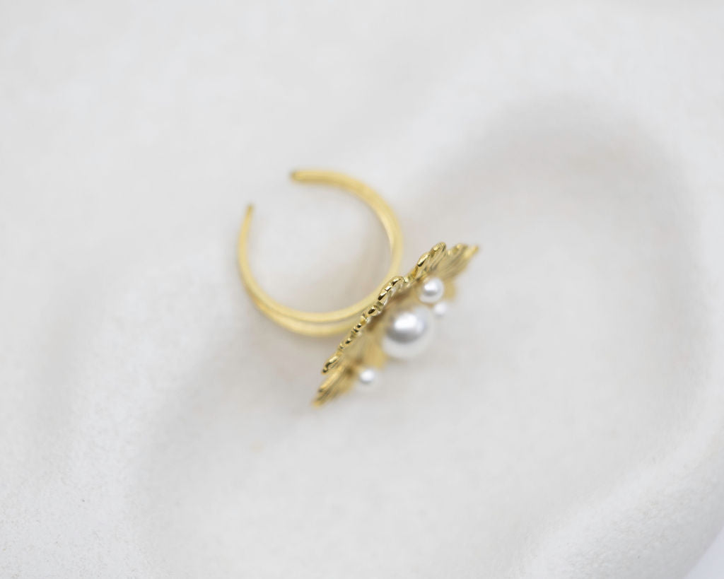 Gold ring with pearl accent on a light gray background