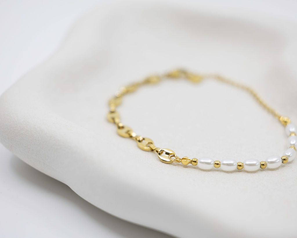 Gold and pearl bracelet on a white surface