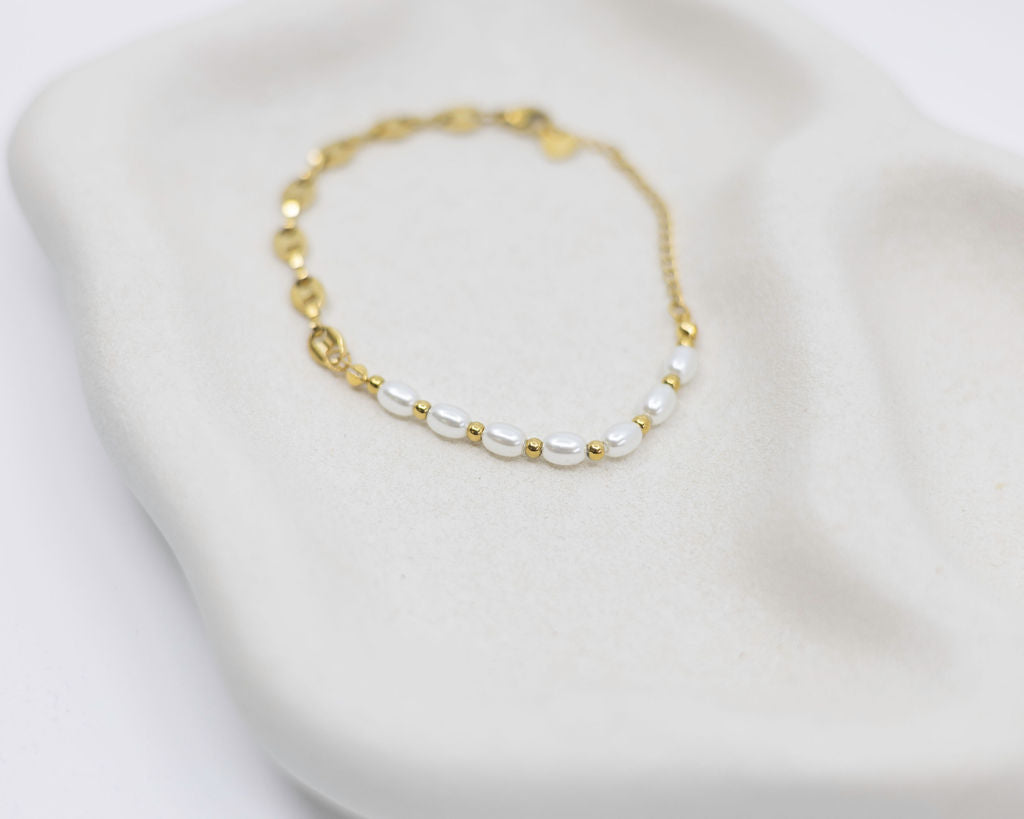 Gold and pearl bracelet on a white background