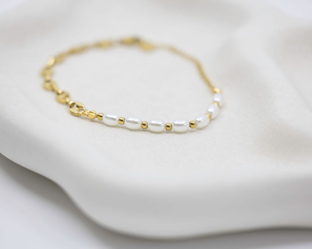 Gold and pearl bracelet on a white surface