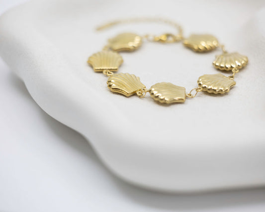 Gold necklace with shell-like pendants on a white surface