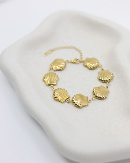 Gold shell bracelet on a white dish