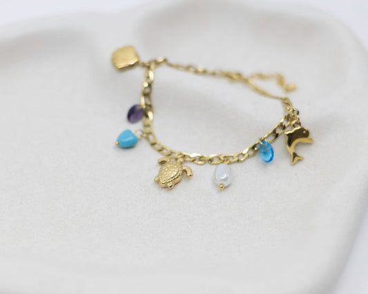 Gold bracelet with various charms on a white background