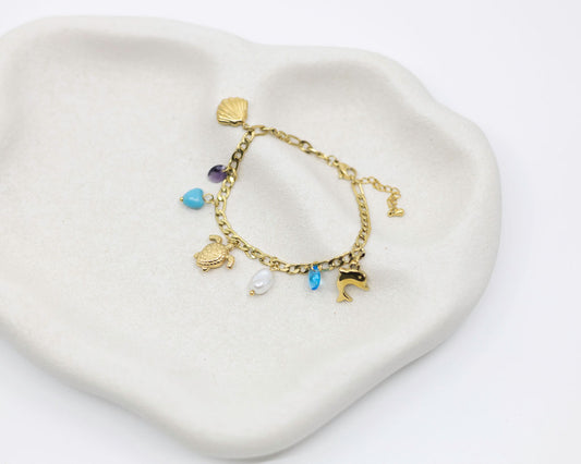 Gold bracelet with charms on a heart-shaped white dish
