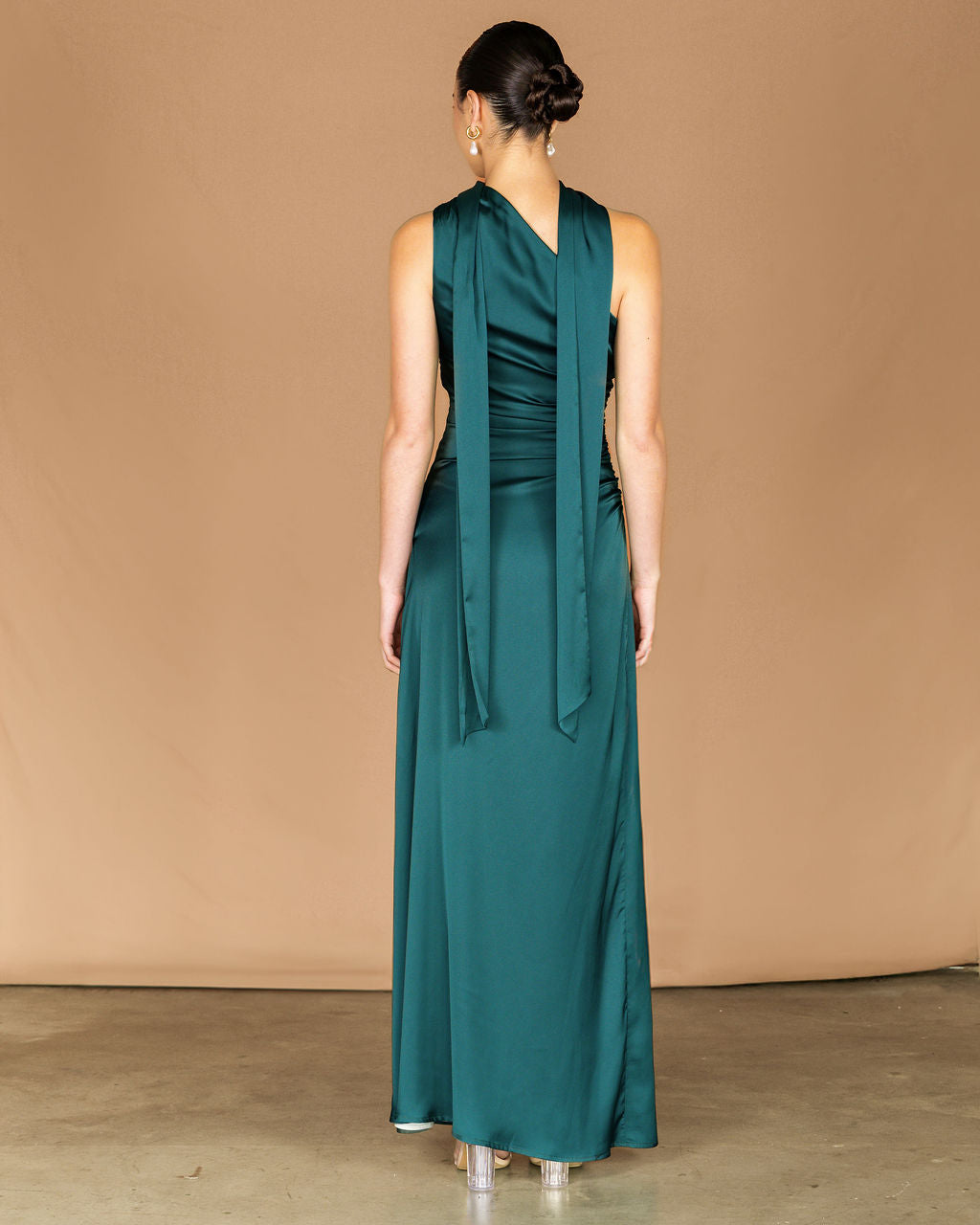 Woman wearing a teal dress against a beige background