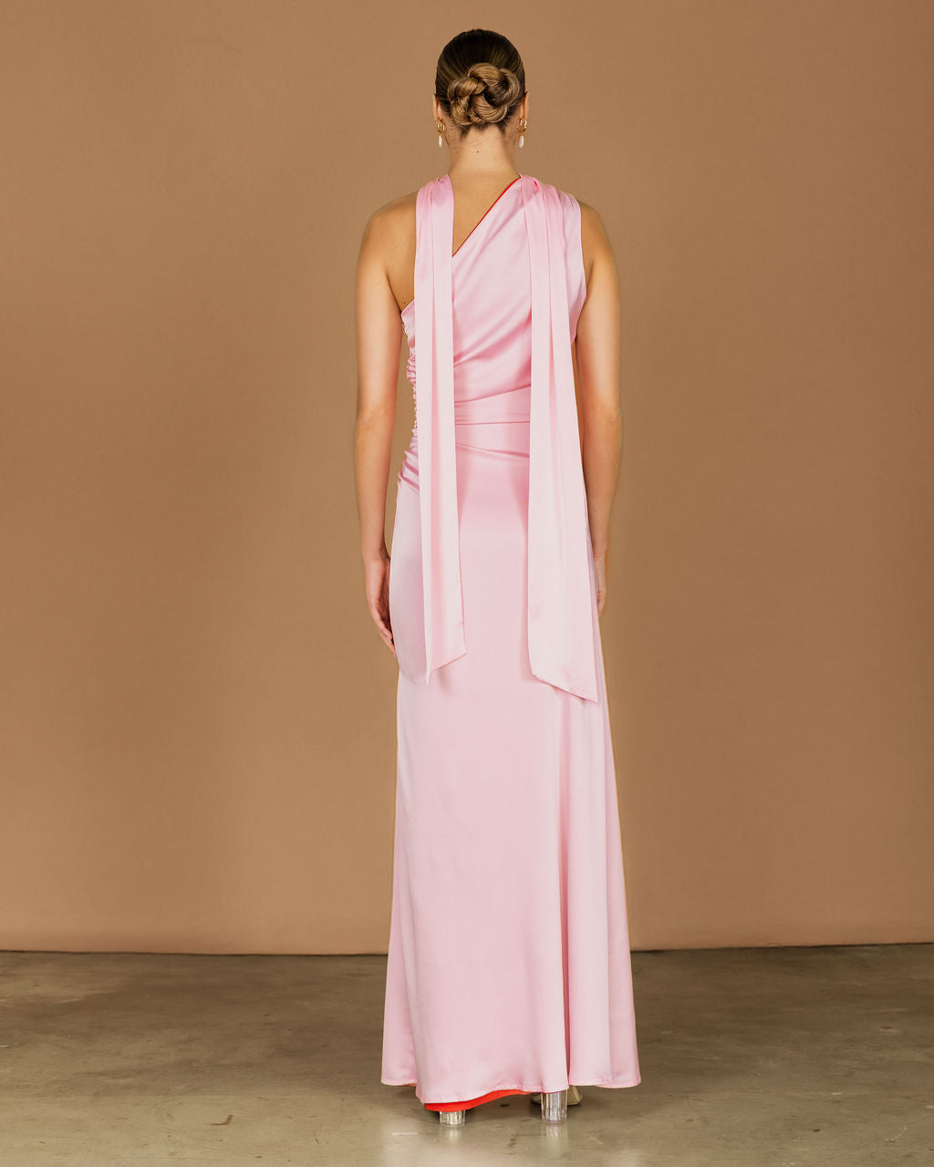 Woman wearing a pink dress with a draped design and sash