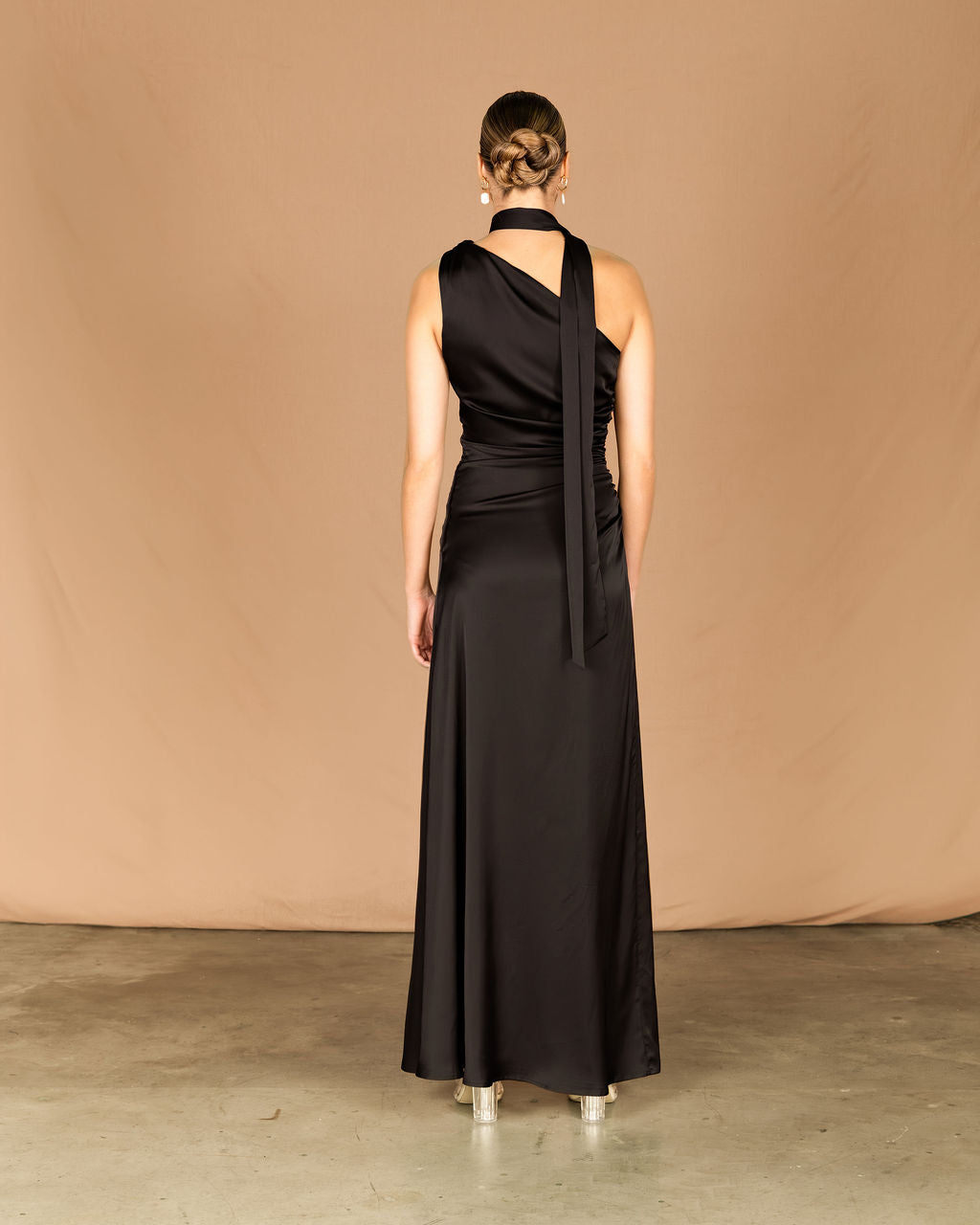Woman wearing a black evening gown with a draped design for a wedding, cocktail, party, ball, school ball